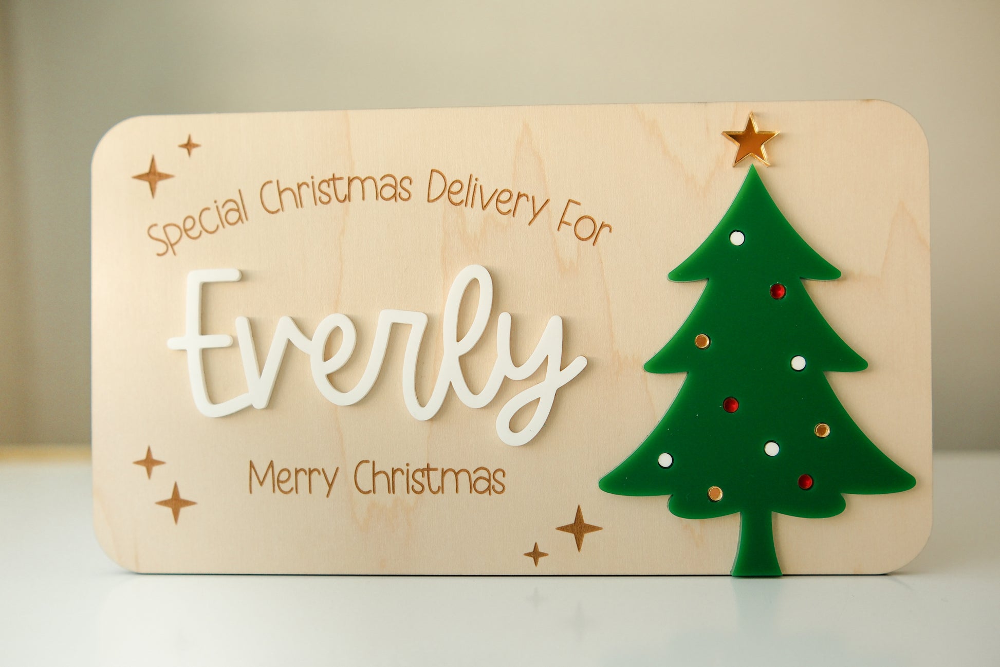 Wooden plaque with 'Special Christmas Delivery For Everly' text and a green tree decoration.