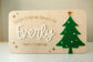 Wooden plaque with 'Special Christmas Delivery For Everly' text and a green tree decoration.